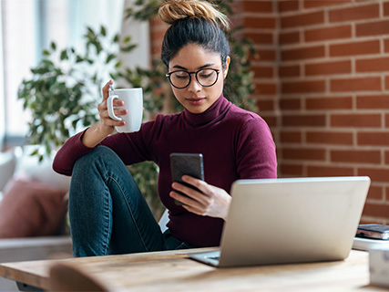 Woman drinking a cup of coffee looking at her phone