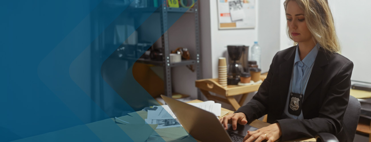 Blonde detective with badge typing on her laptop