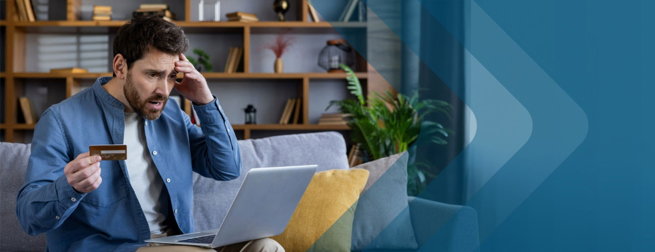 Concerned man wearing blue shirt with hand on head holding credit card