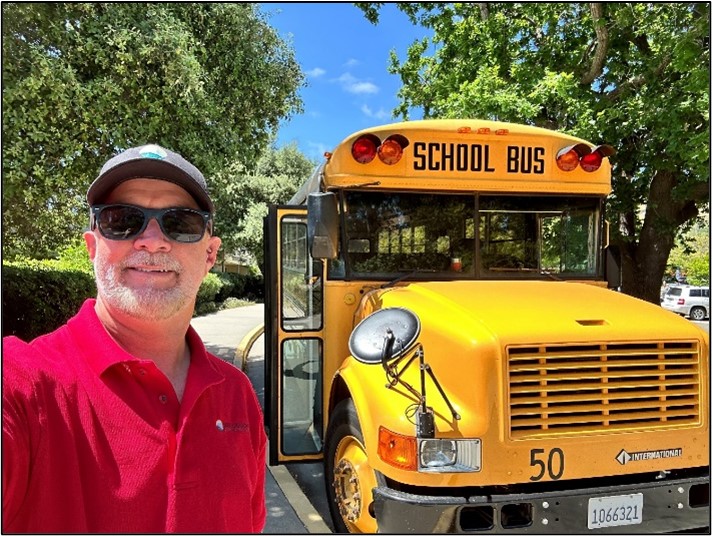 Photo of Ted, a man standing outside in front of a school bus.